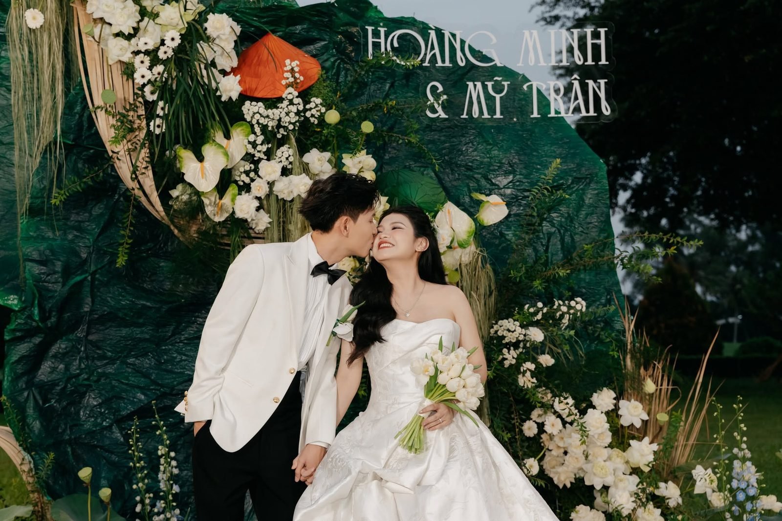 Hoàng Minh & Mỹ Trân under a lush floral arch